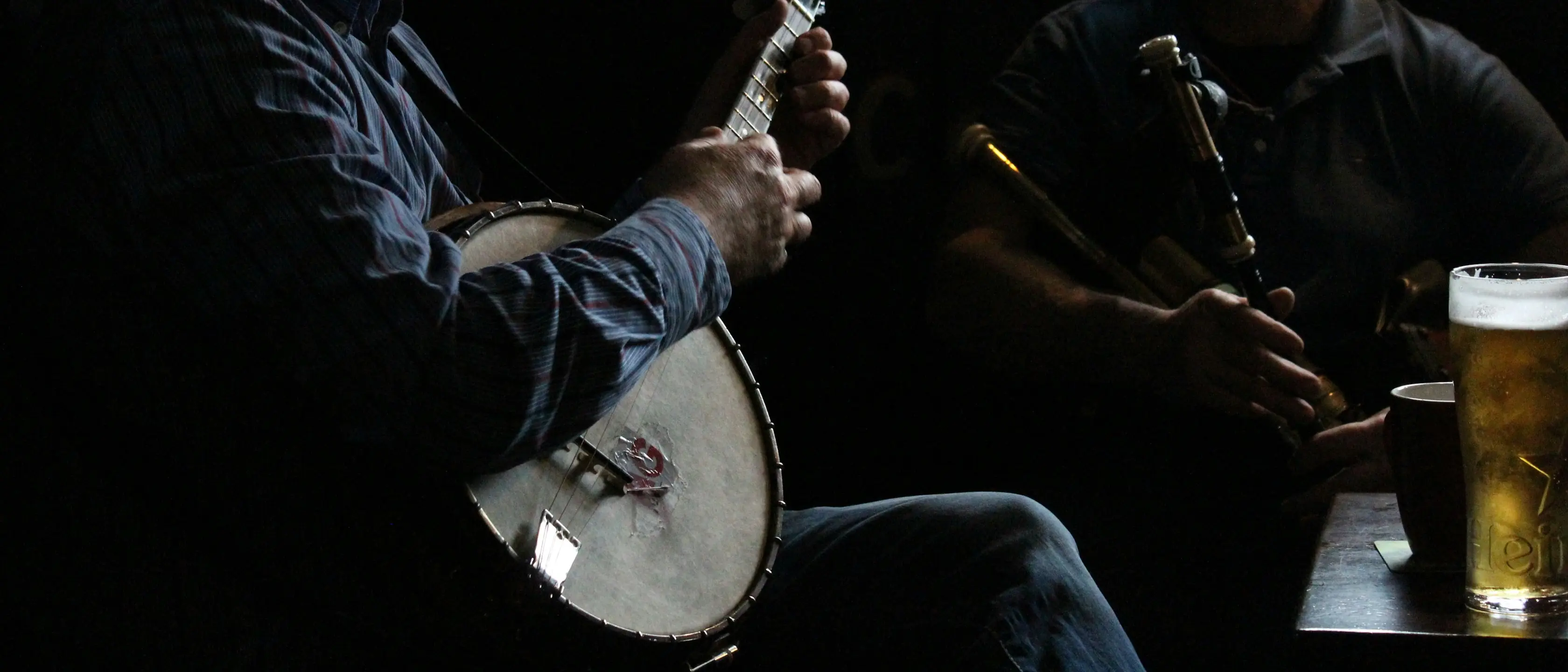 Ein Musiker spielt Banjo, daneben steht ein Glas Bier.